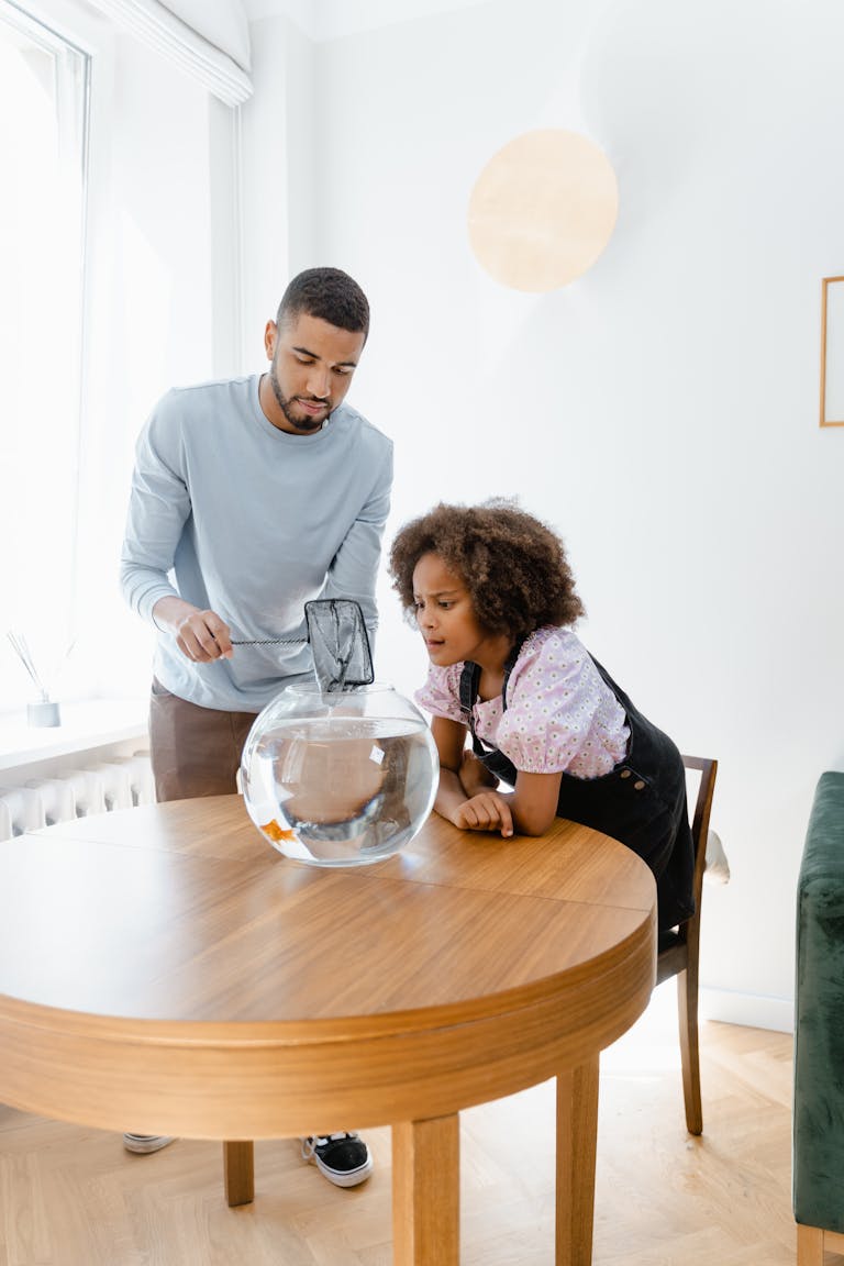 A father and daughter bonding over aquarium maintenance at home, enjoying the hobby together.